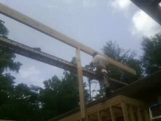 Carpenter setting a ridge beam over a new addition frame — Ice Dam Removal by Roofing Brothers in Barrington