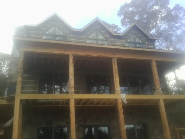 Dormers and porch framing on a large log home under construction — Roof Coating work by our crew in Barrington